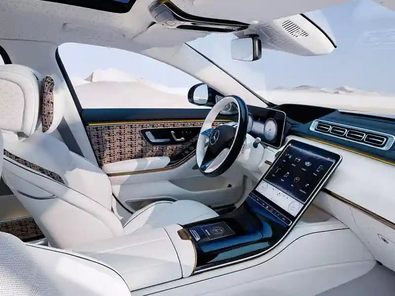 A wide interior view of a limited edition Mercedes-Maybach "Haute Voiture" cabin, featuring white leather seats with bouclé fabric accents in blue and gold, a two-tone steering wheel, and a high-tech digital interface.