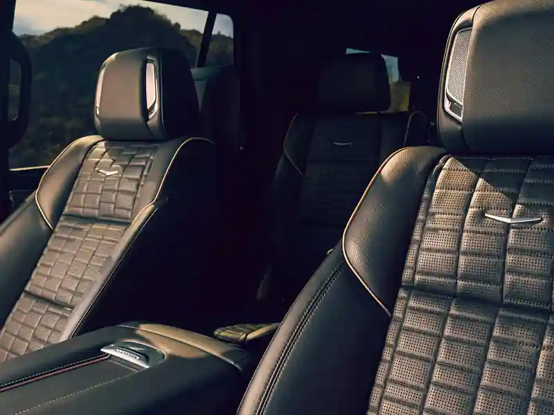 Interior view of a luxury SUV featuring black quilted leather seats with intricate stitching, integrated headrest speakers, and a spacious rear cabin designed for premium passenger comfort.