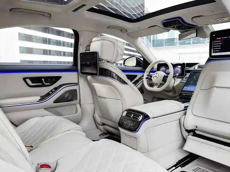 A high-angle close-up of the Rolls-Royce Ghost interior, featuring the bespoke analog clock integrated into the dashboard, set against dark open-pore obsidian wood veneer and white leather upholstery.