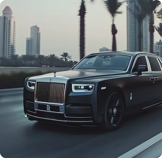 A sleek matte black Rolls-Royce Phantom driving at high speed on a city highway, featuring a prominent chrome grille, Spirit of Ecstasy hood ornament, and a blurred background of palm trees and modern skyscrapers.