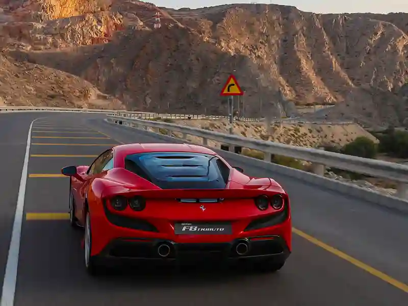 Red Ferrari on the road to the mountains