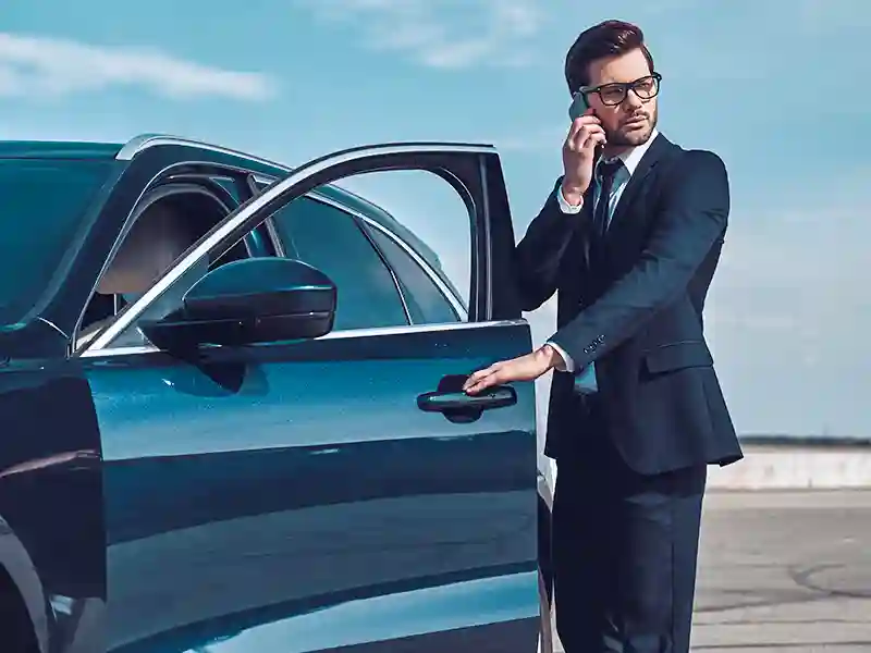 A man in a suit opening the door of a Luxury car