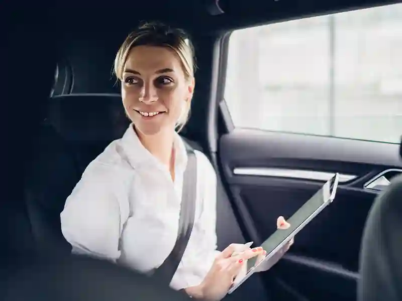 An elegant woman dressed in white on the back seat of the Range Rover Chauffuer Service