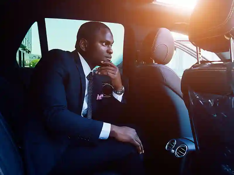 A Black man dressed in a navy blue suit waiting to arrive to his destination