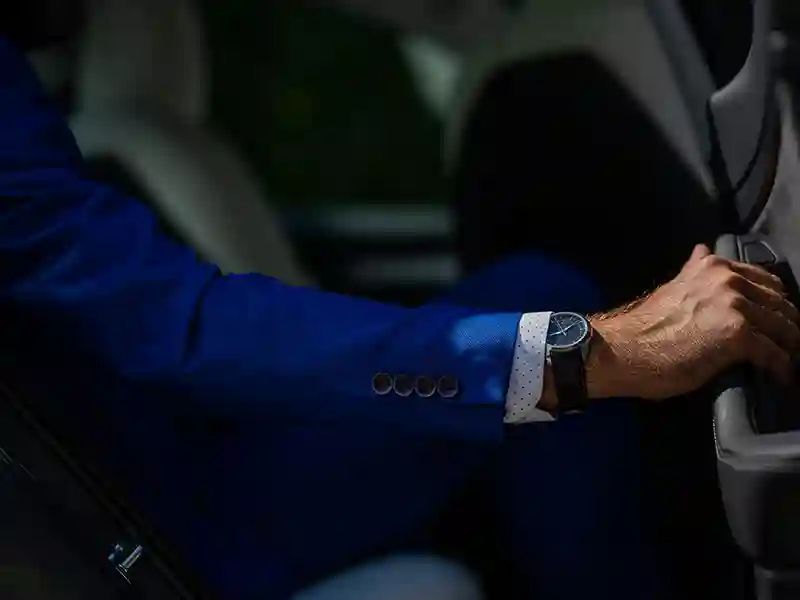 A great close-up of the arm of a man dressing in a blue suit and showing his watch