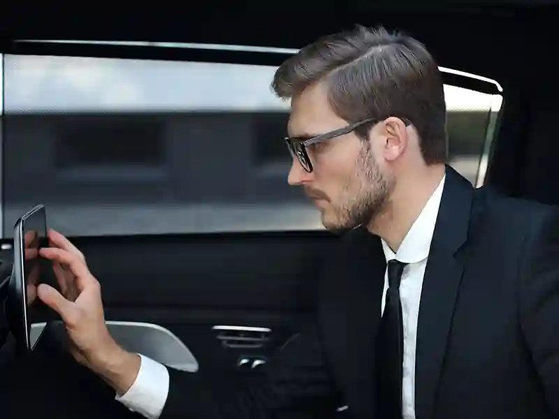 Close-up of a man dressed in a suit and trying to interact with his screen on the back seat