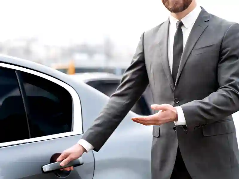 A chauffeur opening the door of a Mercedes-Benz Maybach grey colour