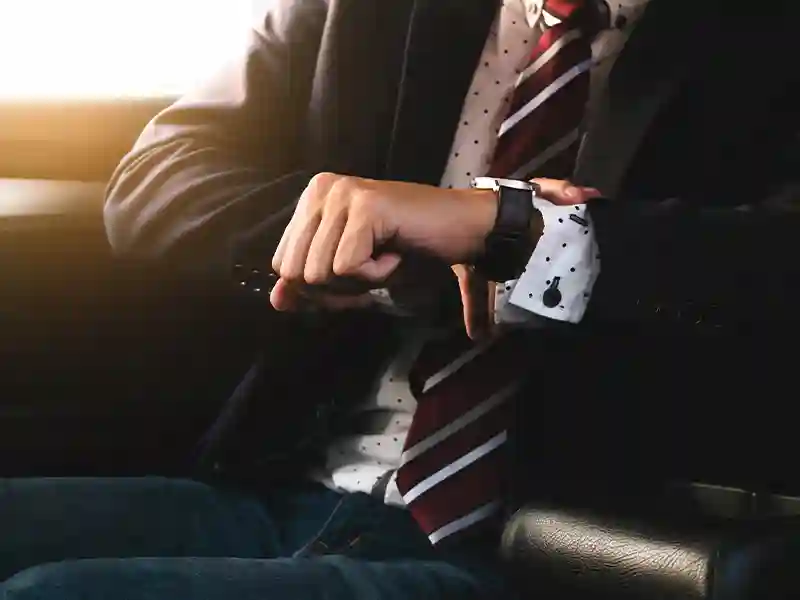 Close-up of the hand of a man wearing a grey suit, who is watching the time