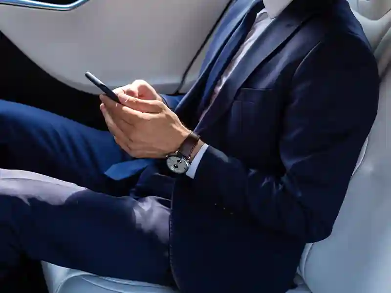 Close-up of the hands of a man using his mobile and dressed in a blue navy suit