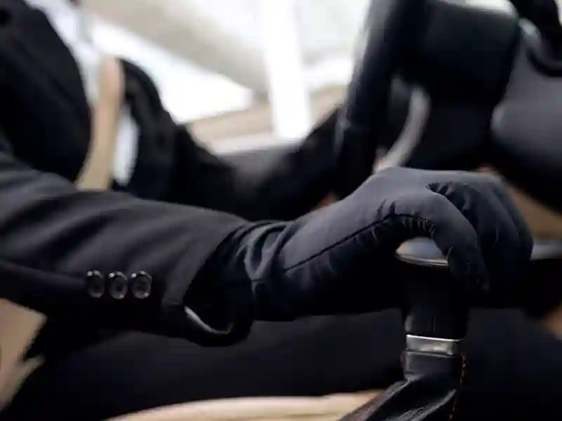 Close-up of the right hand of a Chauffeur, hand on the gear lever and the other hand on the steering wheel