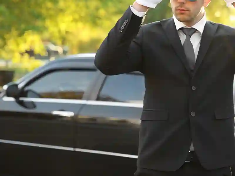 Chauffeur dressed in black with white gloves touching his hat