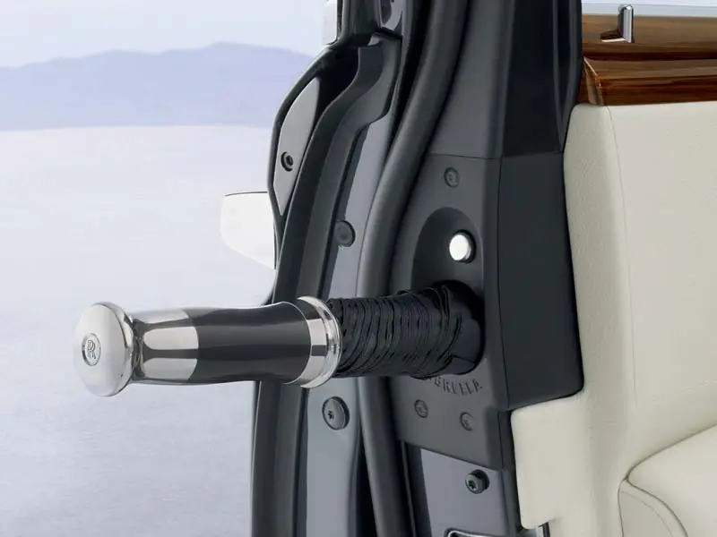 An inviting view into the rear of a Rolls-Royce with the rear-hinged coach door open, displaying plush white leather seating, deep pile carpeting, and premium wood door cappings.