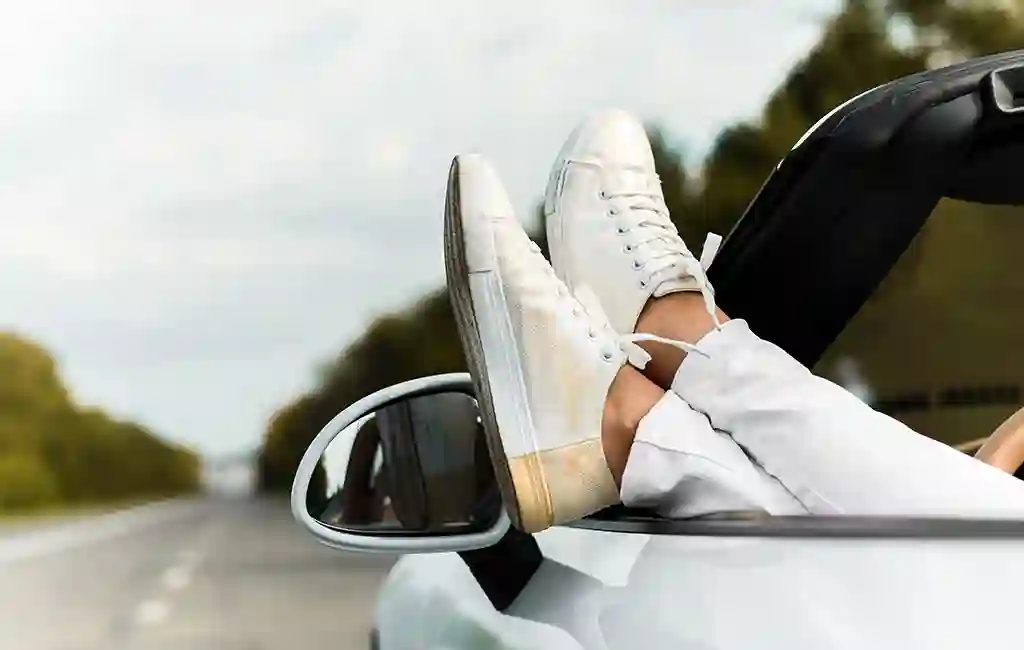 A pair of foot over the window of a convertible